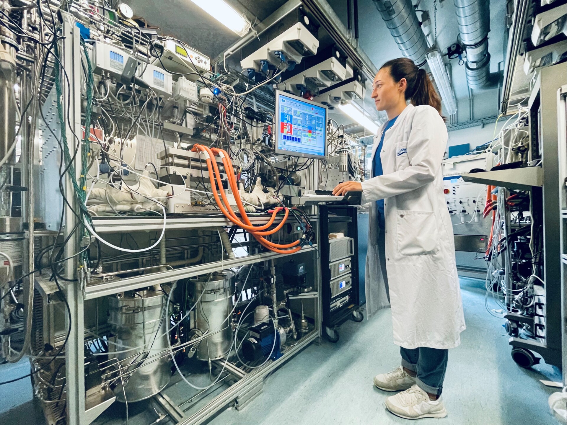 Labor mit Teststand für Brennstoffzellen, eine Wissenschaftlerin überwacht die Test am Computer
